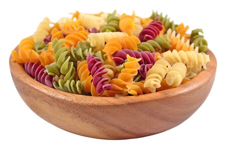 Colored uncooked italian pasta fusilli in a wooden bowl on a white backgroundの写真素材