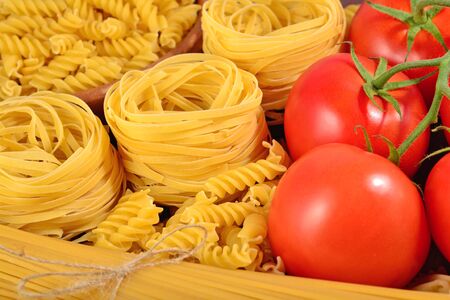 Uncooked Italian pasta and ripe tomatoes branch close upの写真素材