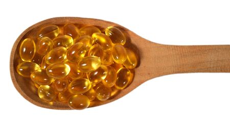 Omega-3 fish fat oil capsules in wooden spoon on a white backgroundの写真素材