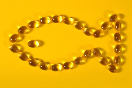 Omega-3 fish fat oil capsules shaped in fish on a yellow background