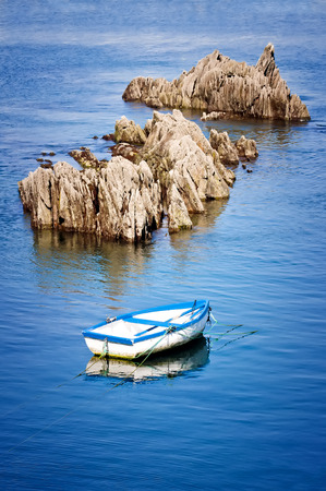 boat moored next to a rock in the harborの写真素材