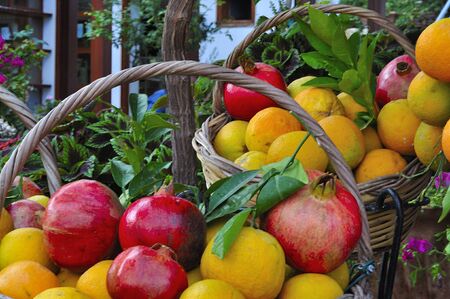 Pomegranates and fresh oranges in a basketの写真素材
