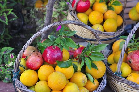 Pomegranates and fresh oranges in a basketの写真素材