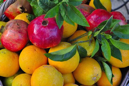 Pomegranates and fresh oranges in a basketの写真素材