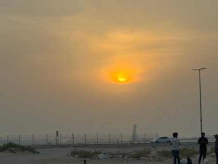 Golden sunset view from a roadside with streetlights and an open horizon, creating a warm and serene evening sceneの写真素材