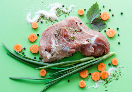 raw piece of meat with spices, with herbs and carrots closeupの写真素材
