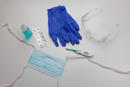 Medical gloves, face mask, protective eye wear, fever thermometer, sanitizing alcohol gel, and...
