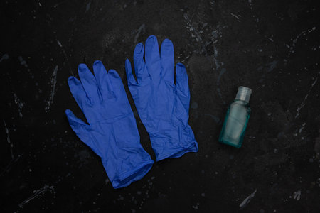 Blue medical gloves and blue hand sanitizing alcohol gel on black