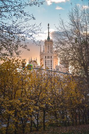 View of the Stalinist skyscraper through the autumn trees at sunsetの写真素材