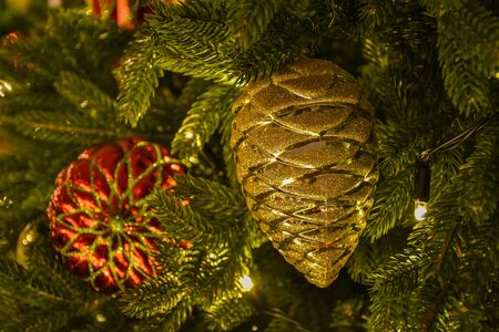 Christmas toy in the form of a golden Christmas cone, toy on Christmas tree branchの写真素材