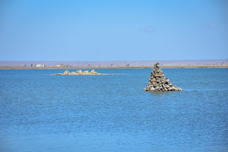 a pile of stones in the middle of the water, a cairn in the lake