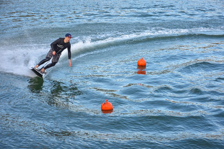 Motosurf Competitor taking corner at speed making a lot of spray. Jet surfing on a water, man riding...