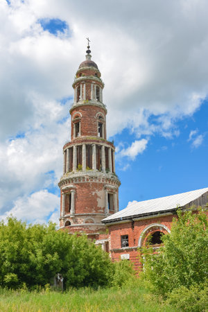 an abandoned dilapidated church, overgrown with grass against the background of the sky, surrounded by greeneryの写真素材