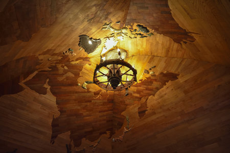 included round chandelier with light bulbs candles on the background of a wooden ceiling in the form...