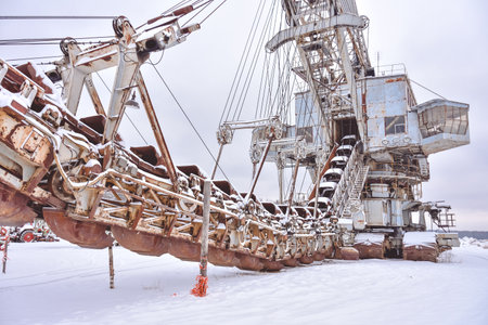 abandoned giant bucket wheel excavator stands in a field in winterの写真素材
