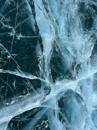 Abstract background of ice and cracks on the surface of frozen Lake Baikal. Spiderweb of cracks on...