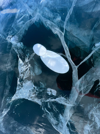 Abstract background of ice and cracks on the surface of frozen Lake Baikal. Spiderweb of cracks on...