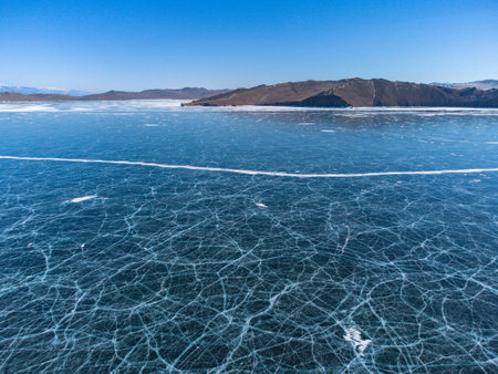 pure ice of the frozen lake Baikal against the background of mountainsの写真素材
