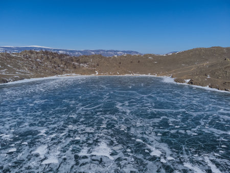 pure ice of the frozen lake Baikal against the background of mountainsの写真素材