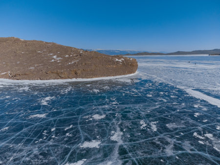 pure ice of the frozen lake Baikal against the background of mountainsの写真素材