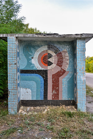 A bus stop with a mural on the wall. The mural is of birds and a sunflowerの写真素材