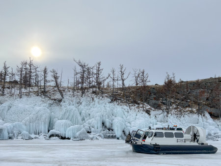 A white boat is on the water in the snow. The boat is moving and the water is frozenの写真素材