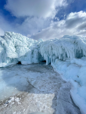 A large ice formation with a blue sky in the background. The ice formation is very large and has a...