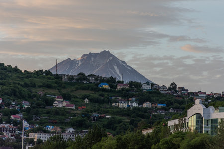 City with a volcano in the background. The volcano is covered in snow. The city is full of buildings and housesの写真素材