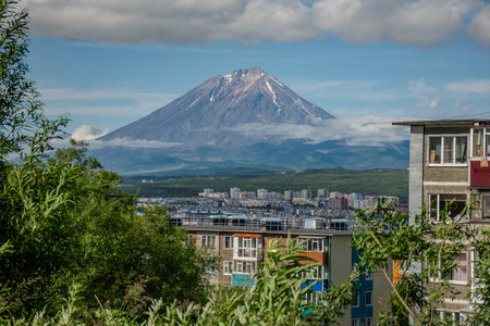 City with a volcano in the background. The volcano is covered in snow. The city is full of buildings...