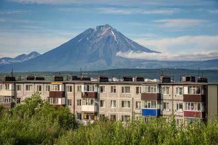 City with a volcano in the background. The volcano is covered in snow. The city is full of buildings...