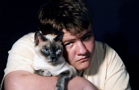Teen boy holding Siamese cat.の写真素材