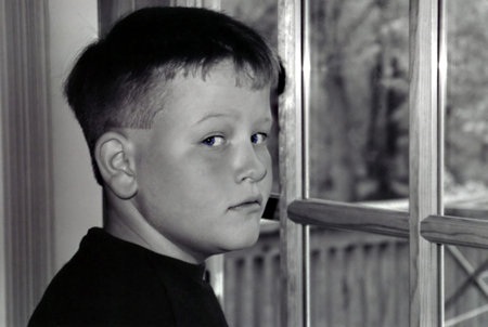 Young boy glancing back from looking out a door.の写真素材