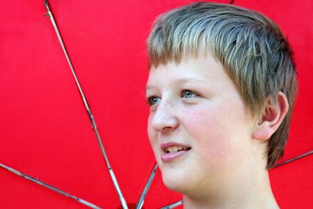 Horizontal portrait of boy holding a red umbrella.の写真素材