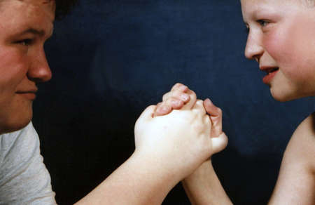 Two boys of different ages preparing to arm wrestle.の写真素材
