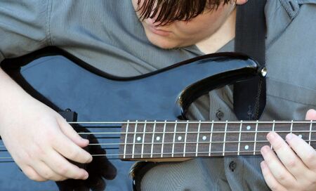 Closeup of teenage boy playing bass guitar.の写真素材