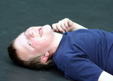 Preteen boy laying on a trampoline acting goofy.の写真素材