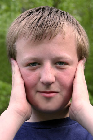 Preteen boy covering both ears with his hands.