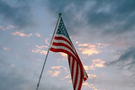 American flag in wind against blue sky and clouds.の写真素材