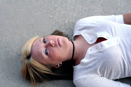 Young blond woman laying on the ground on a concrete background.の写真素材