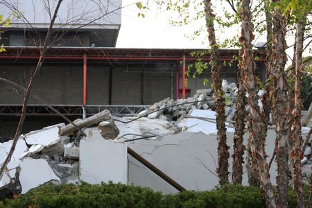 Pile of remnants of a building demolition piled in front of the partially demolished building.の写真素材