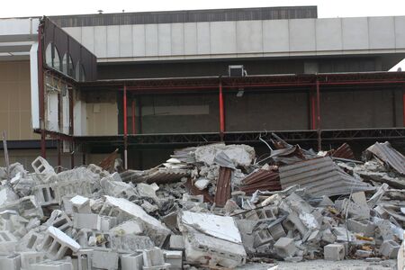 Remnants of a building demolition piled in front of the partially demolished building.の写真素材