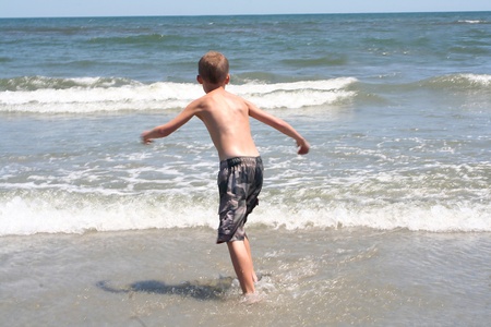 Back view of a 9 year old boy running into the surf at the beach in Wildwood, New Jersey.の写真素材