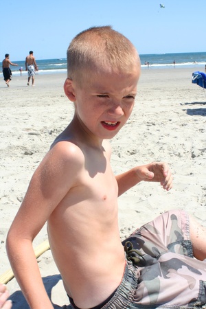 9 year old boy sitting on the beach in the process of digging with his hands in Wildwood, New Jersey.の写真素材