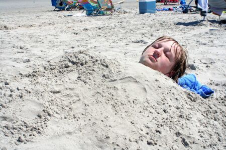 Teen Boy Buried in Sandの写真素材