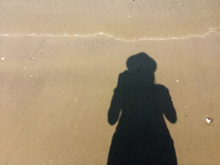 Girl photographer's shadow on the sand