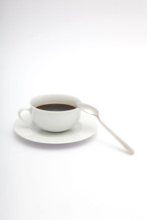 A white cup of coffee with a metal spoon on a white backgroundの写真素材