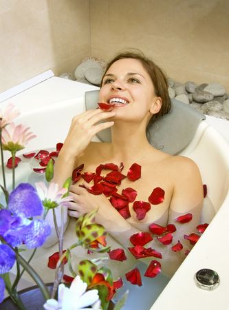 happy beautiful woman lies in bath with rose-petalsの写真素材