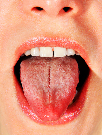opened mouth of woman with put her tongue outの写真素材