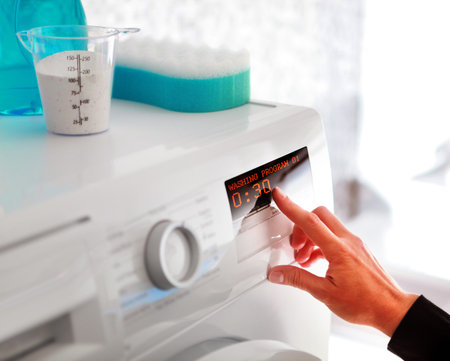 Close up of woman hand choosing program for washing machineの写真素材