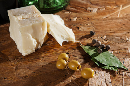 parmesan cheese and green olives with other spices on wooden surfaceの写真素材